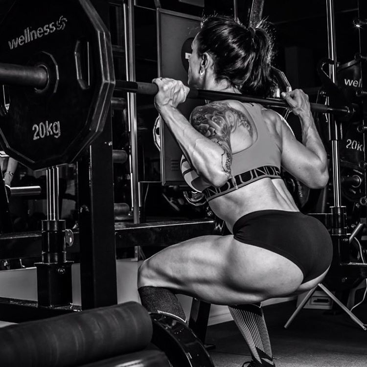 Renata Costa doing heavy squats in a gym looking strong and lean